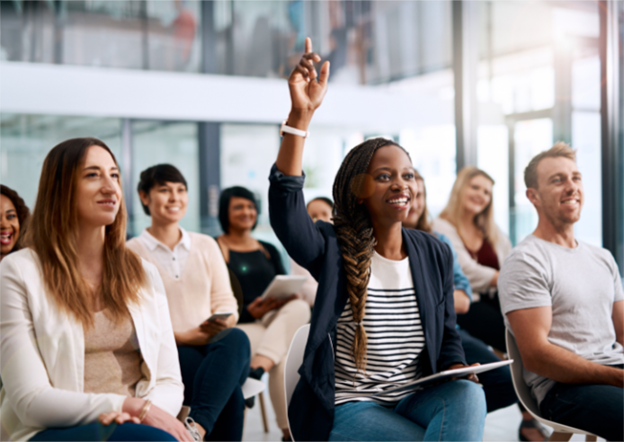 group of people sitting in chairs, one raising their hand